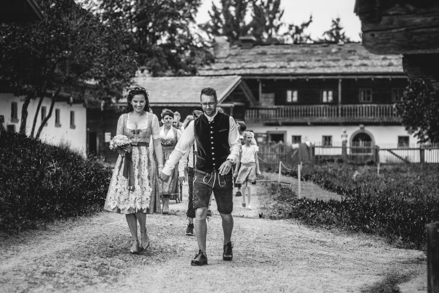 Hochzeit im Museumsdorf Tittling, Paar in Tracht läuft an Spitze von Hochzeitsgesellschaft