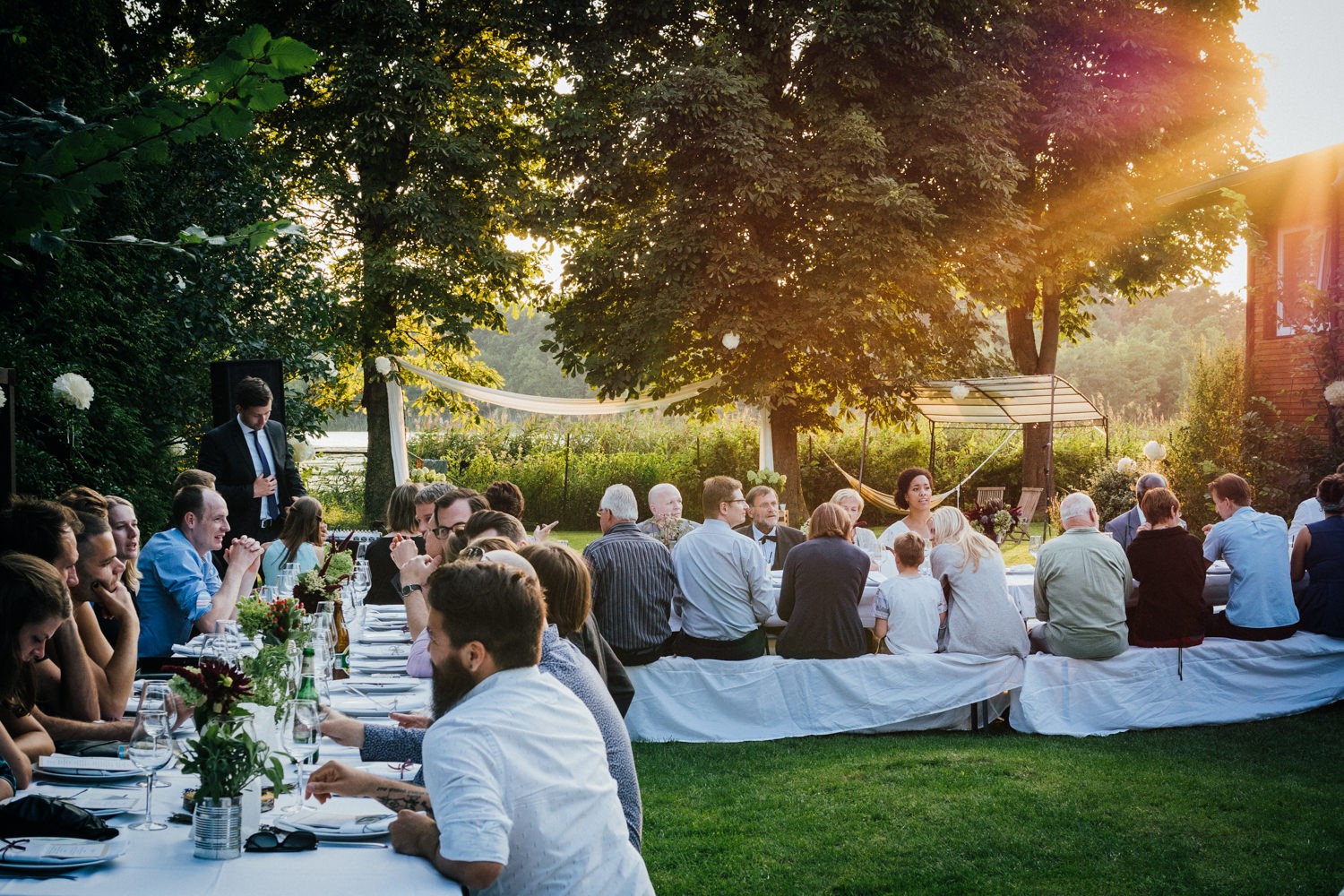 Hochzeit in Dobbrikow, die Gäste sitzen bei Sonnenuntergang an ihren Tischen und unterhalten sich