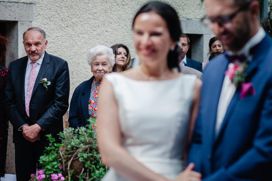 Hochzeit im Gut Aichet bei Passau, freie Trauung, Großmutter schaut zufreiden und wohlwollend zur Braut