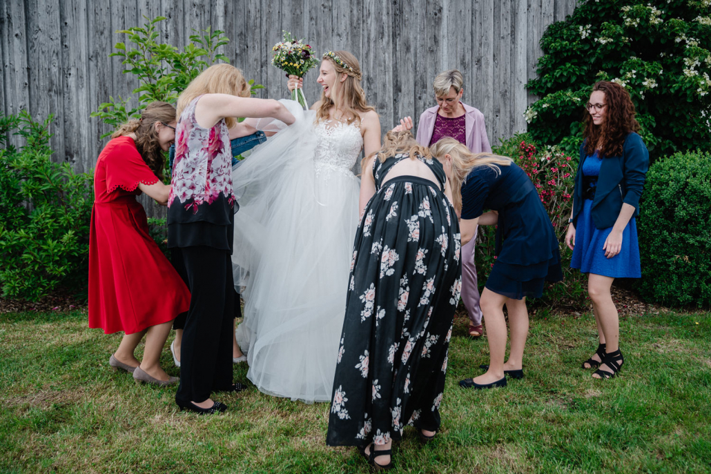 Hochzeit in Fürstenzell und Untersimbach, Paarshooting, die weiblichen Gäste richten das Kleid der Braut