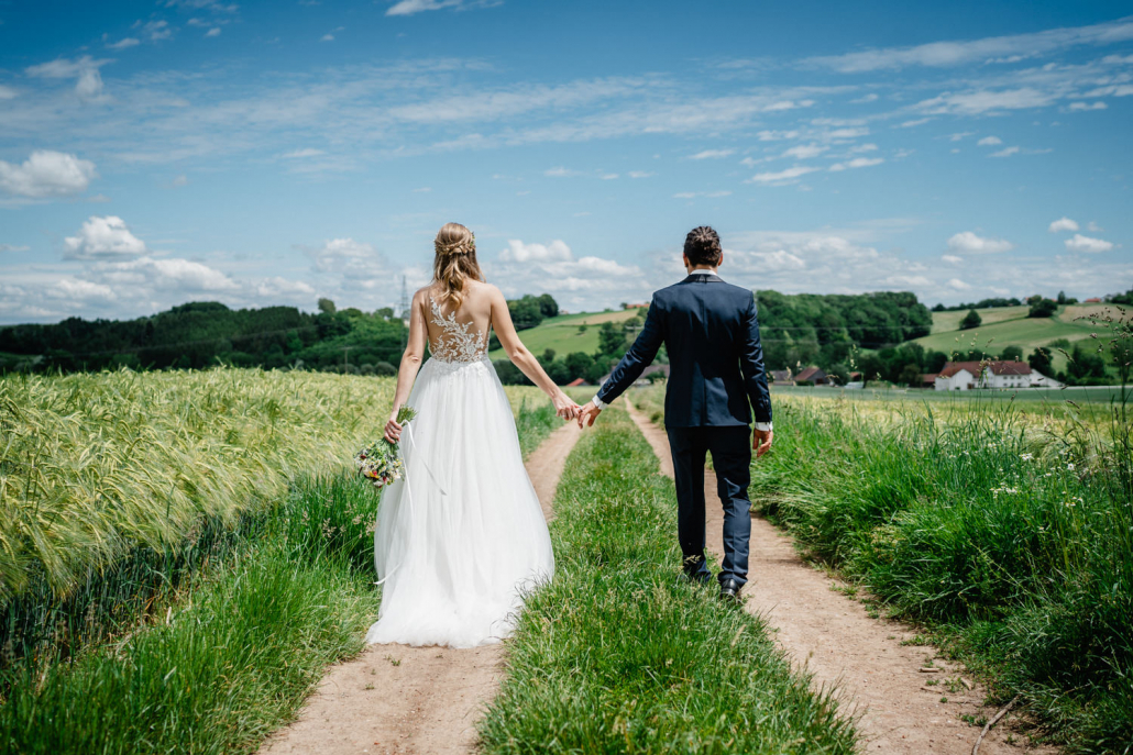 Hochzeit in Fürstenzell und Untersimbach, Paarshooting, Brautpaar läuft Hand in Hand über Feldweg