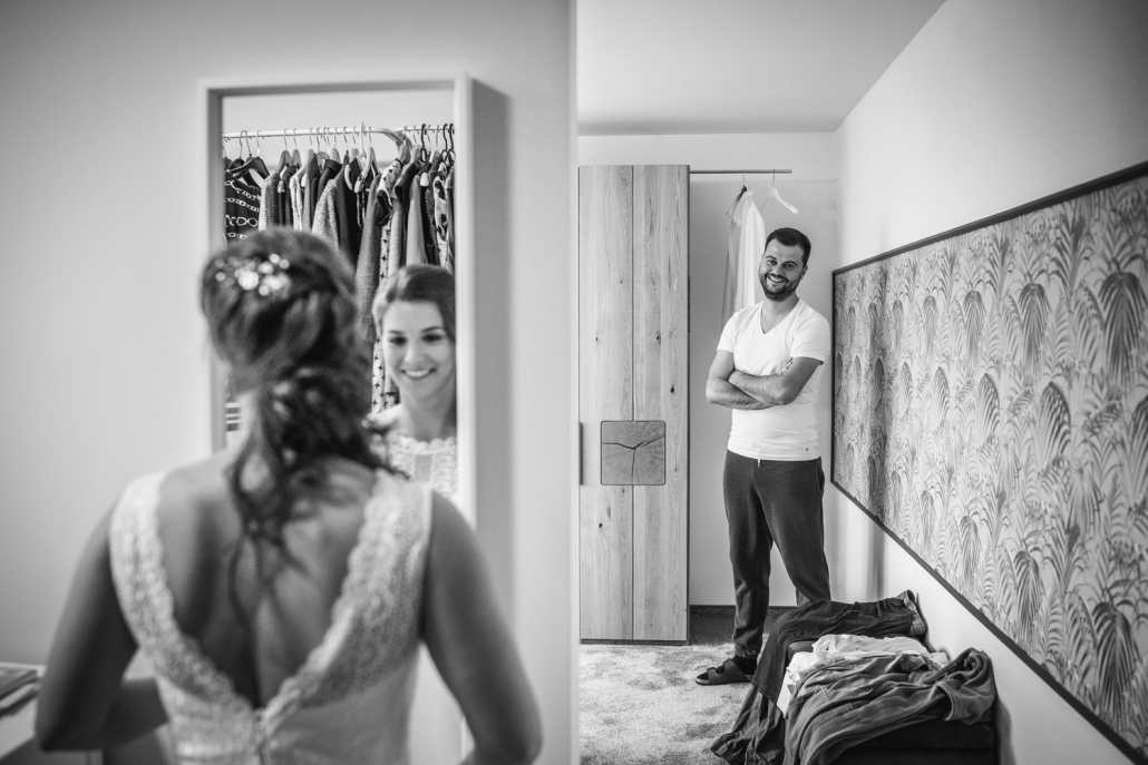 Hochzeit in Bad Birnbach, Getting Ready in Osterhofen, Braut betrachtet sich im Spiegel, Bräutigam blickt zu ihr