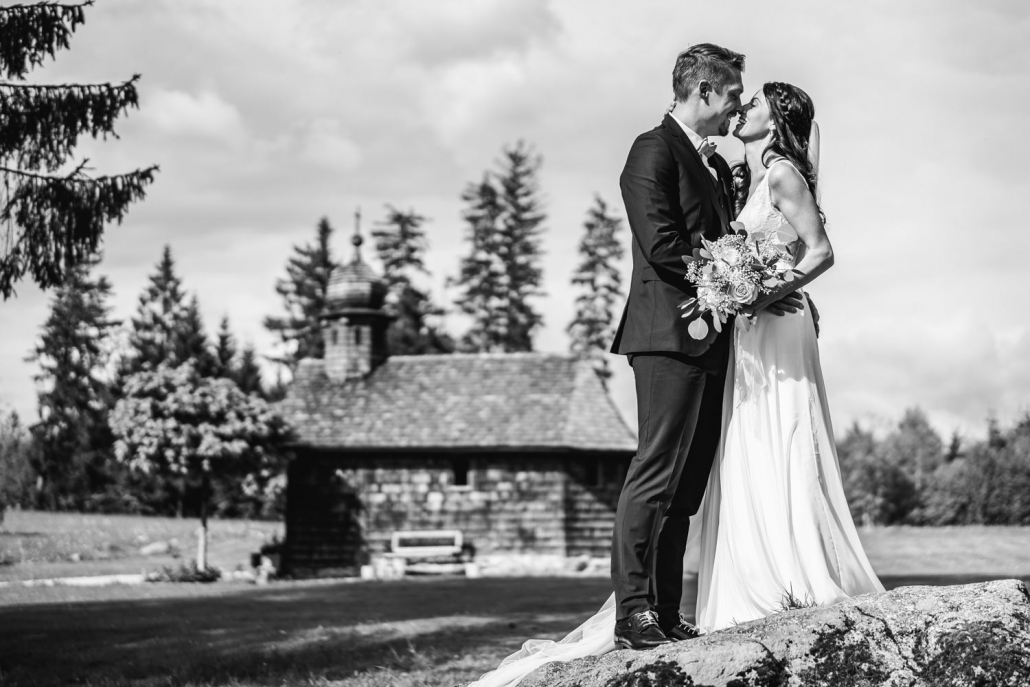 Hochzeit Gutsalm Harlachberg, Paarshooting, Paar steht vor Holzkirche