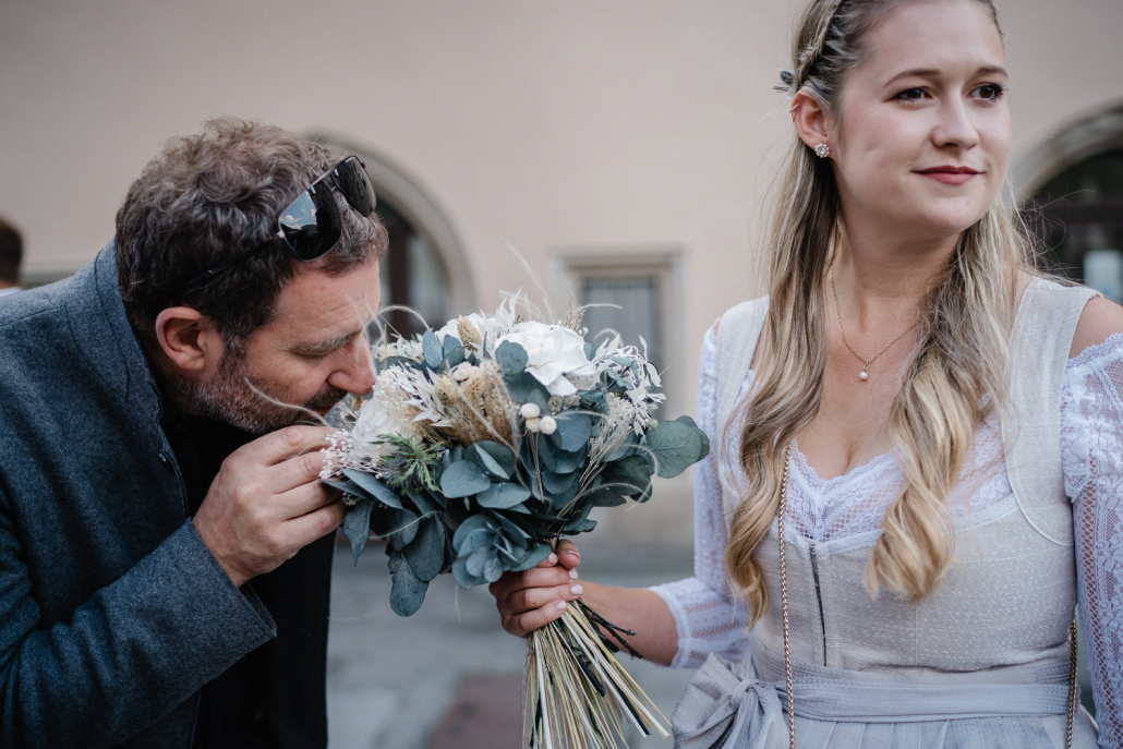 Hochzeit im Standesamt Passau, Gast der Trauung riecht am Brautstrauß