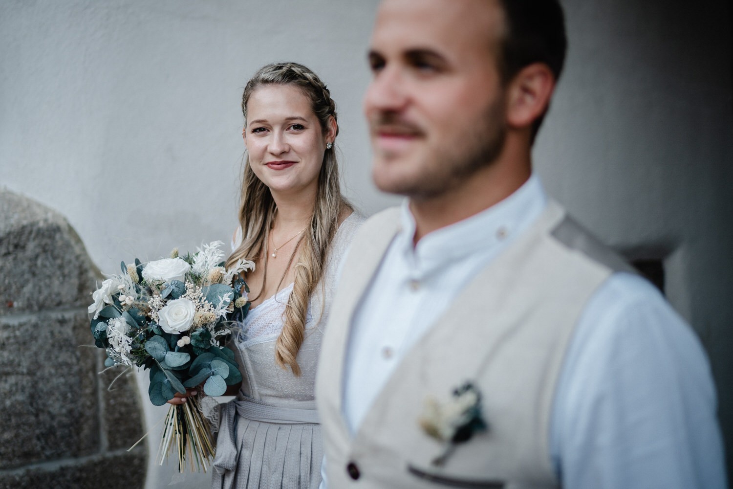 Hochzeit in der Veste Oberhaus Passau, Paarshooting, Braut schaut in die Kamera, Bräutigam ist unscharf im Vordergrund