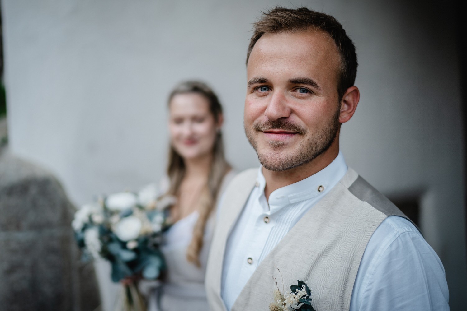 Hochzeit in der Veste Oberhaus Passau, Paarshooting, Bräutigam schaut in die Kamera, Braut ist unscharf im Hintergrund