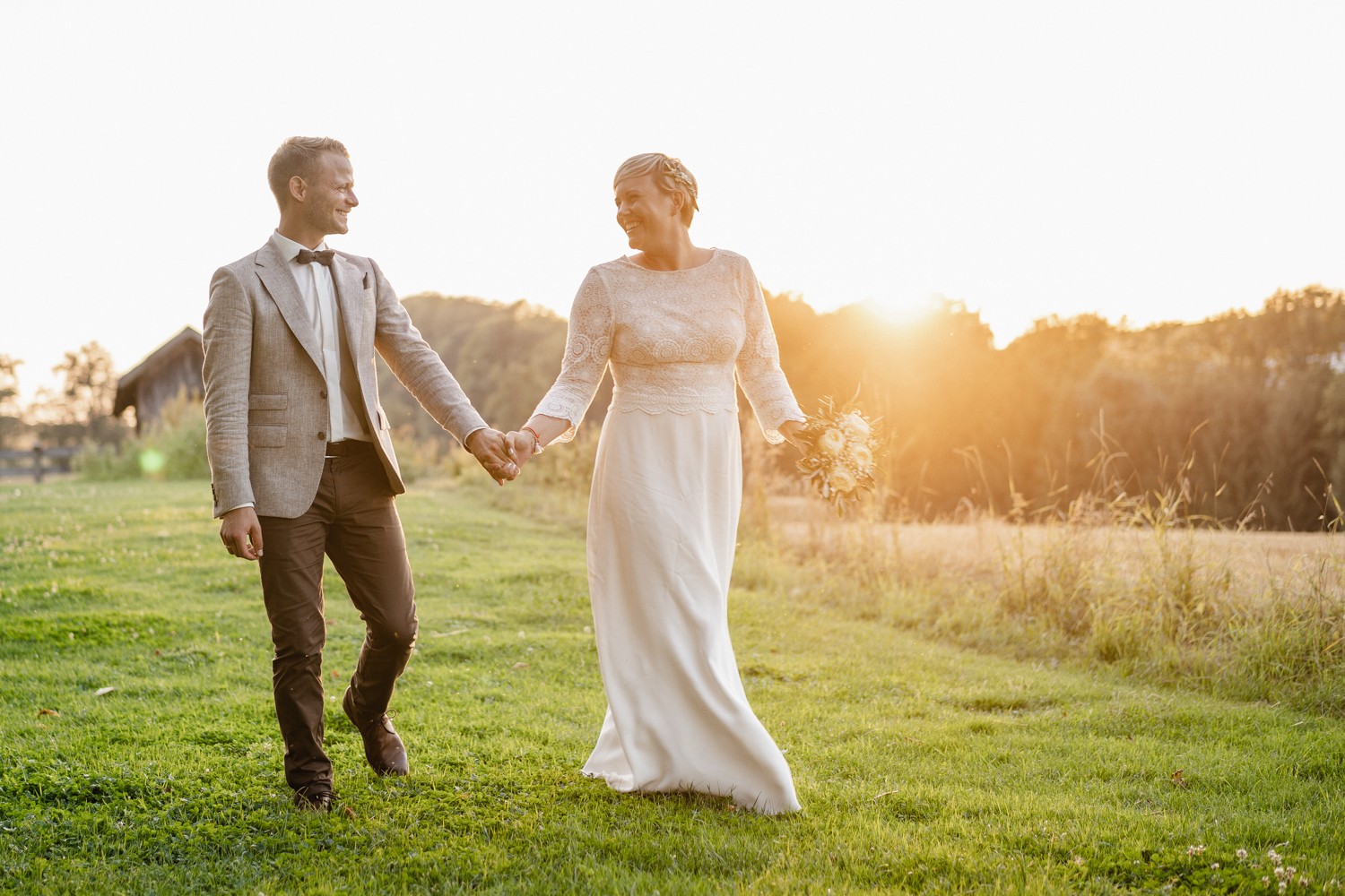 Hochzeit auf dem Rahaberghof, Oberösterreich, Paarshooting, Brautpaar läuft Hand in Hand bei Sonnenuntergang
