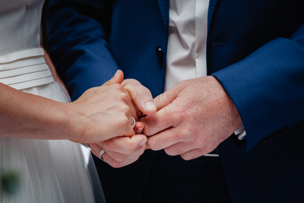 Hochzeit auf Gut Aichet, das Brautpaar hält sich an den Händen