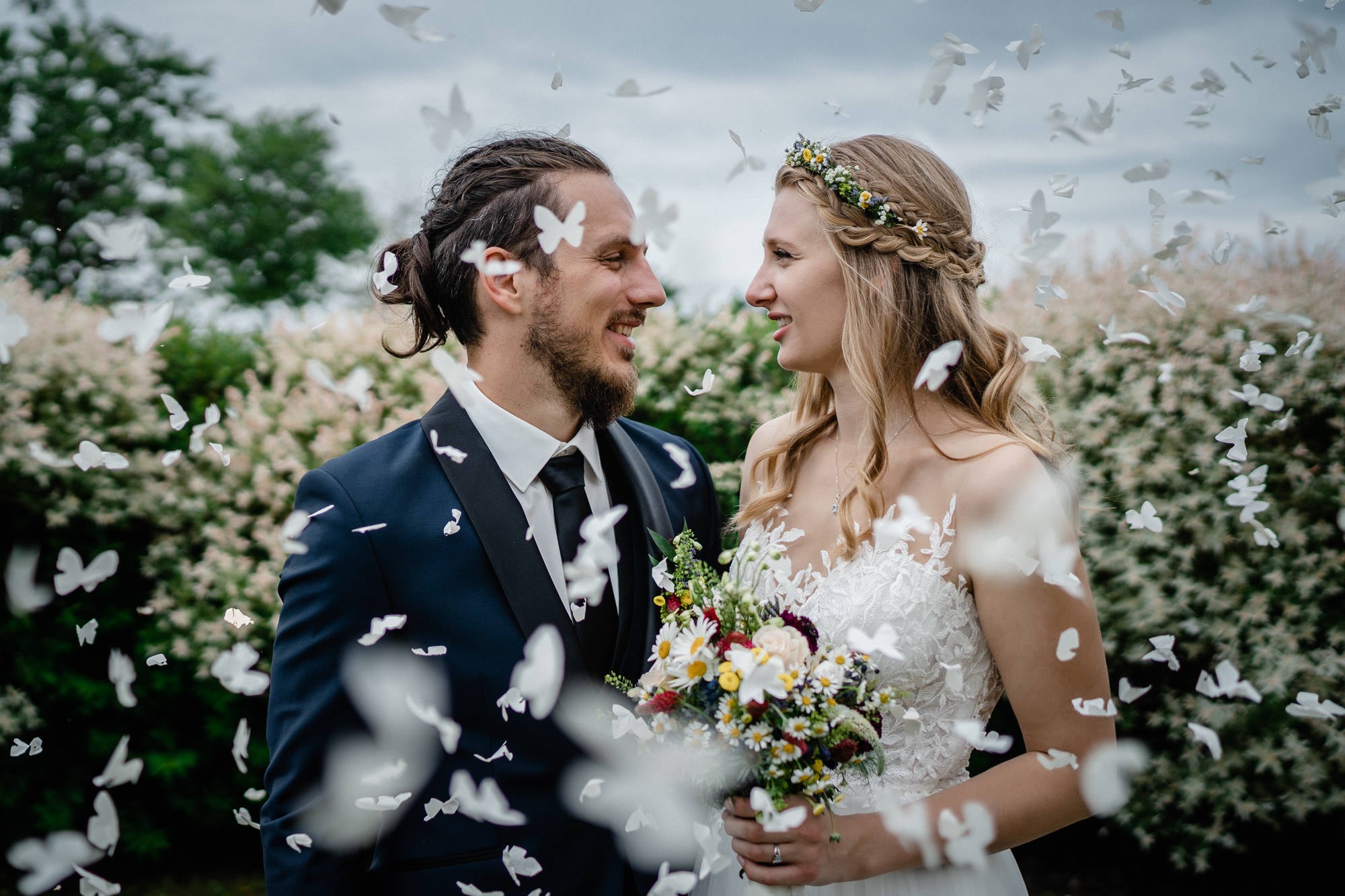 Hochzeit in Fürstenzell, Brautpaarshooting, Brautpaar steht zwischen fliegenden Papierschmetterlingen