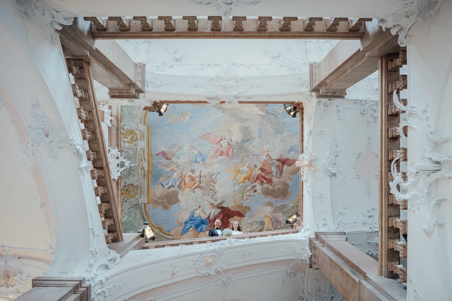 Das Brautpaar blickt von der Treppe hinuter