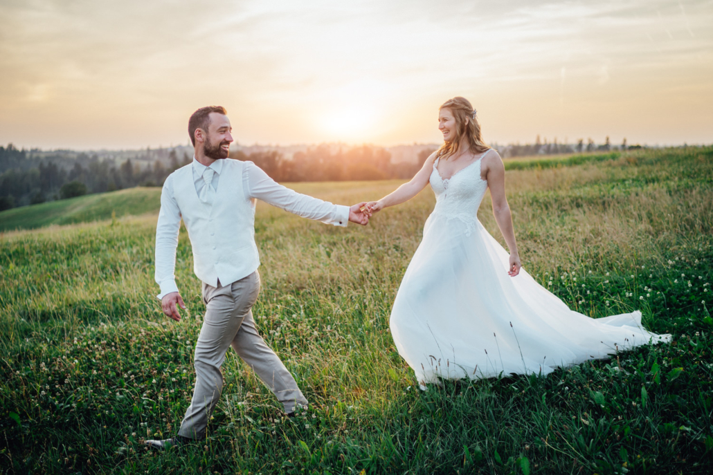 Brautpaar beim Hochzeitsshooting am Gasthof Waldbauer in Haag bei Hauzenberg bei Sonnenuntergang läuft über eine Wiese